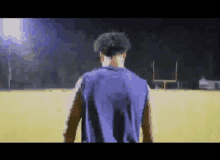 a football player is walking on a field at night .