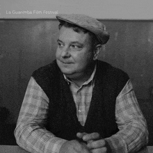 a man wearing a plaid shirt and a hat is sitting at a table with the words la guarimba film festival written above him