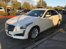 a white cadillac is parked in a parking lot with a california tag