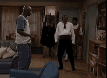 a group of men are standing in a living room dancing together .