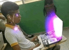 a boy is sitting at a desk with a laptop and headphones on .