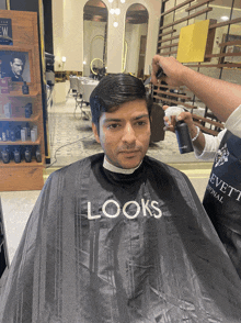 a man is getting his hair cut by a looks barber