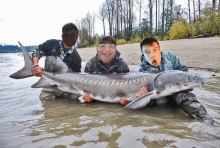 two men are holding a large fish in the water with their faces obscured