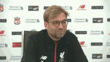 a man wearing glasses and a jacket that says liverpool