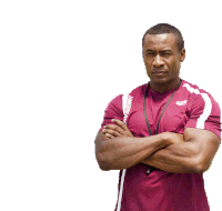 a man standing with his arms crossed wearing a maroon shirt that says asics on the front