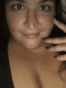 a woman with purple nails and a nose ring smiles for the camera