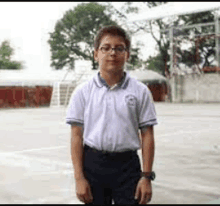 a young boy wearing glasses and a white shirt is standing on a court .