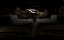 a man and a woman sit in a dark room looking at each other