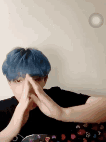 a person with blue hair is covering their nose with their hands