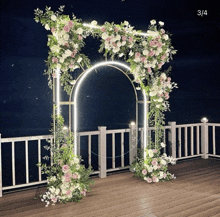 a wooden deck with a white railing and a floral arch with the number 3/4 below it