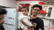 a man wearing glasses is holding a baby in his arms .