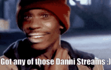 a man wearing a red beanie is smiling and says got any of those danni streams .