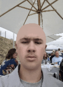 a bald man is standing under an umbrella