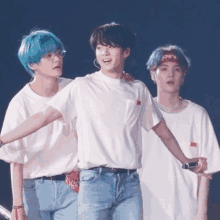 three boys with blue hair are standing next to each other on a stage .