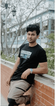 a man leaning against a wall wearing a black shirt that says casual time