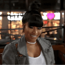 a woman wearing a plaid jacket and a choker is smiling while sitting at a table .