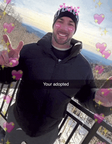 a man wearing a black jacket and a black hat with hearts on his face says your adopted