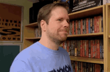 a man in a blue shirt stands in front of a shelf full of dvds and a sign that says cinema digital sound