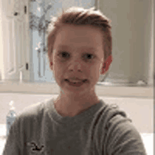 a young boy is taking a selfie in the bathroom .