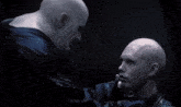 a bald man is holding another bald man 's face