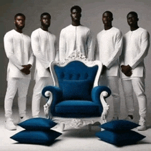 a group of men standing in front of a blue chair