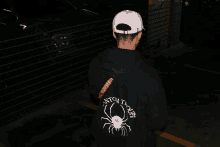 a person wearing a black hoodie with a spider and the word supreme on the back