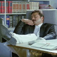 a man in a suit is sitting at a desk with his feet up in front of a bookshelf that has tax books