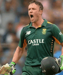 a cricket player is holding his helmet and screaming while wearing a castle lager shirt .