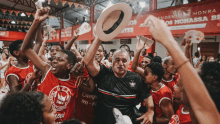 a man holding a hat surrounded by people wearing red shirts with the word camp on them