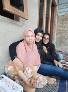 three women are posing for a picture in front of a building with a sign that says ' a' on it