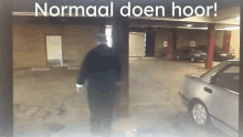 a man walking in a parking garage with the words " normaal doen hoor " written above him