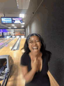 a woman laughs in a bowling alley with a bowling alley sign above her