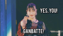 a woman pointing at the camera with the words yes you ganbatte