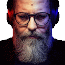 a man with a beard and glasses is wearing headphones and looking at the camera .