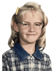 a little girl wearing glasses and a plaid shirt smiles for the camera