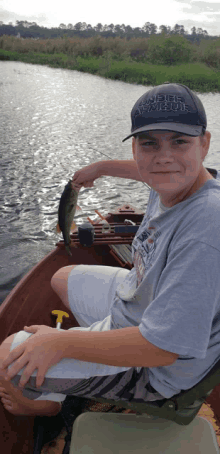 a boy wearing a hat that says ' jeep adventure ' on it is holding a fish