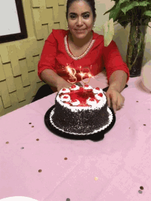 a woman in a red shirt is blowing out candles on a birthday cake that says ' 38 ' on it