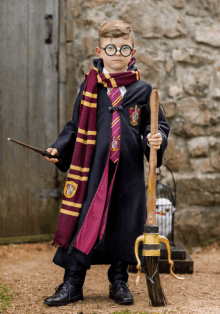 a young boy dressed in a harry potter costume is holding a wand and a broom