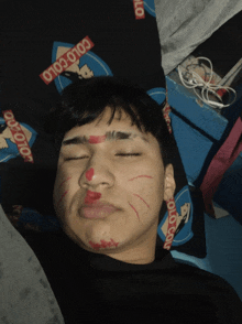 a young man with red paint on his face is laying on a bed with a colo colo blanket