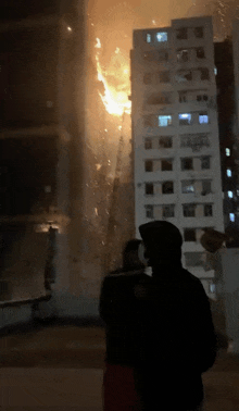 a man stands in front of a burning building