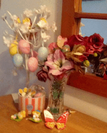 a vase filled with flowers sits on a table next to a box of candy