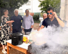 a man wearing sunglasses is standing in front of a grill