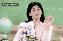 a woman is sitting at a desk in front of a blackboard holding a copy of romeo and juliet .