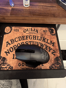 a mouse sits on a ouija board with the letters abcdefghijklm nopqrstuvwxyz on it