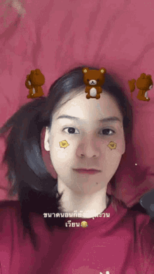 a girl with a teddy bear on her forehead is laying on a pink blanket