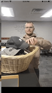 a man is standing next to a wicker basket filled with baseball caps .