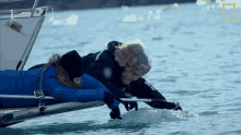 a man and a woman laying on a boat in the water with a national geographic logo in the background