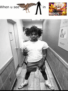 a black and white photo of a man standing in a hallway next to a picture of an eagle and a ninja