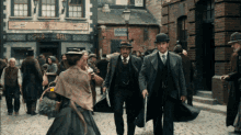 a group of people walking down a cobblestone street in front of a building with a sign that says ' the bee '