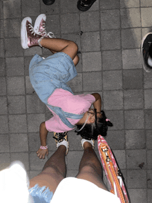 a little girl wearing a pink shirt and overalls laying on the ground